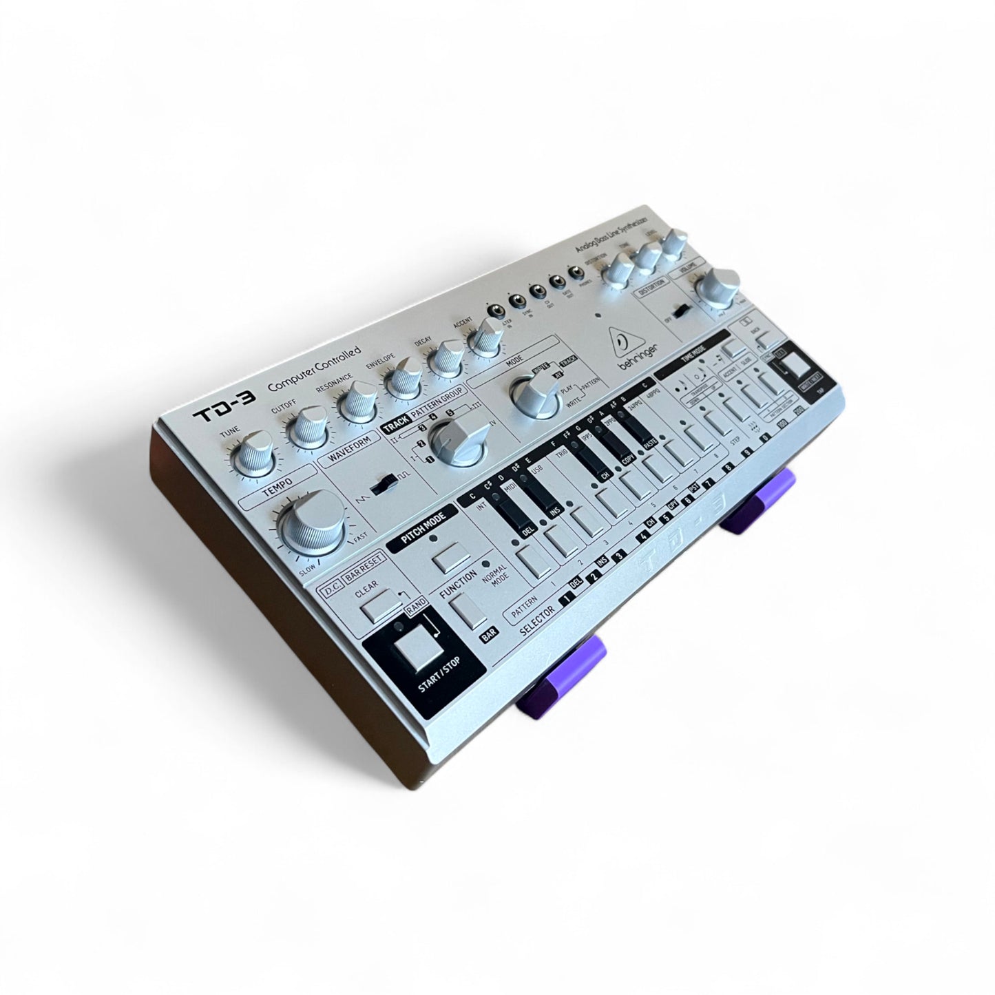 3D printed Behringer TD-3 / RD-6 / RD-78 Synth 30 degree stand by Cold Earth Industries, shown in purple on a white background holding a TD-3