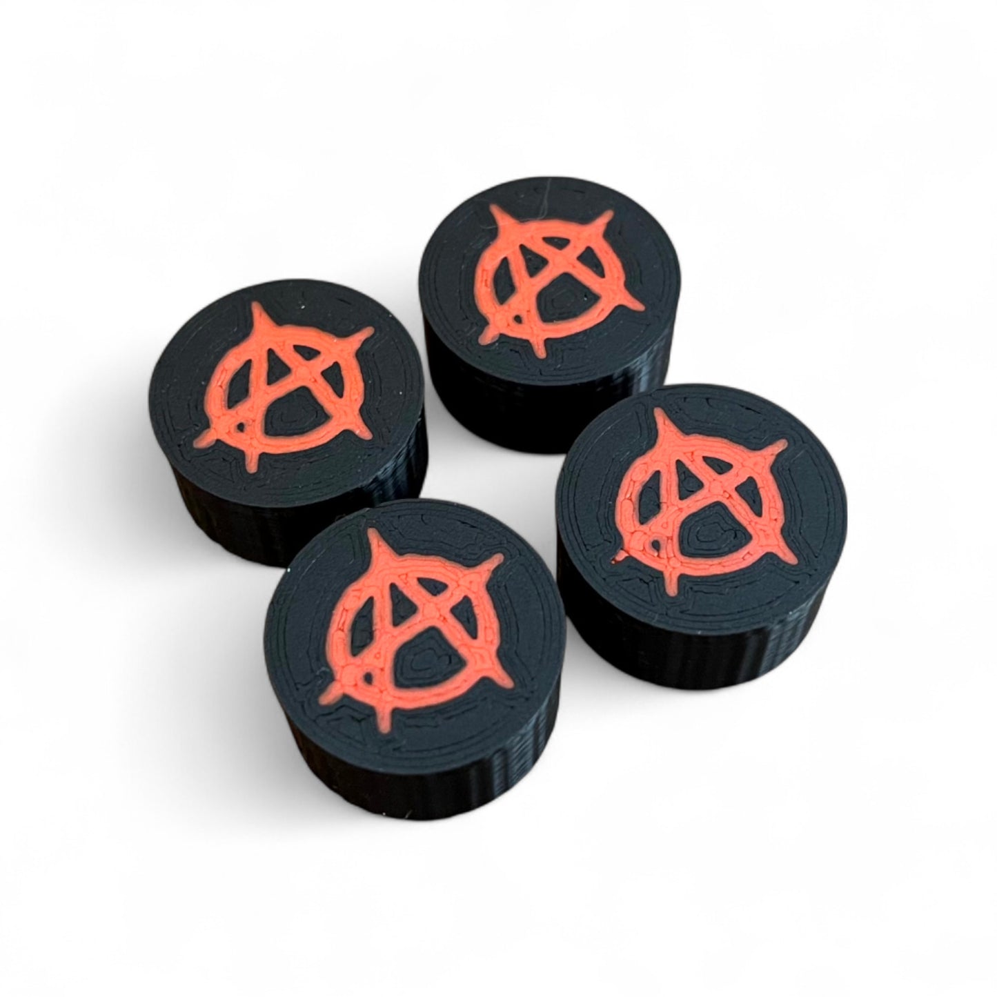3D printed Anarchy Sign Guitar Pedal Footswitch Topper by Cold Earth Industries, 4 shown in black with a red anarchy symbol on a white background.