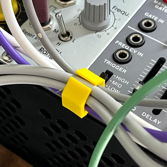 Close-up of a eurorack modular synthesizer with cables and a yellow eurorack cable clip.