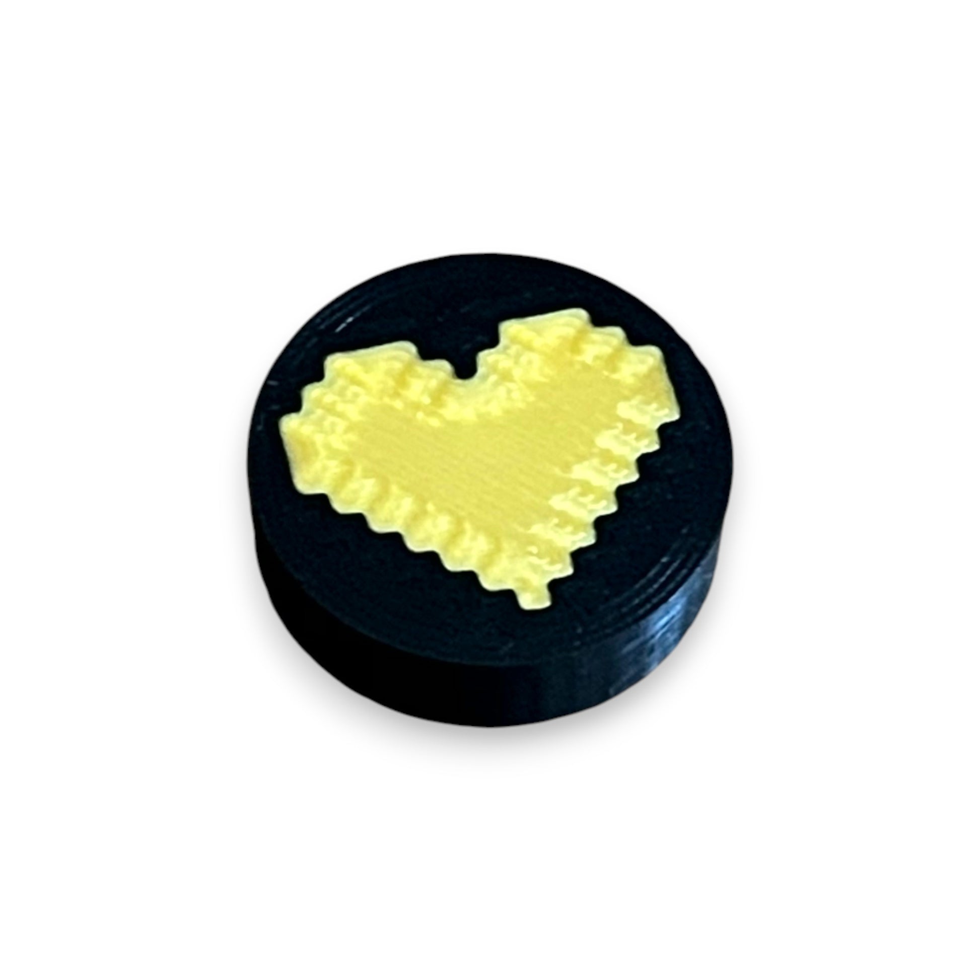 Black and Gold Heart Low Profile Guitar Pedal Footswitch Toppers for 8.5mm / 10mm / 11mm Foot Switches. 3D printed by Cold Earth Industries, shown on a black topper with a gold heart icon on top, against a white background.