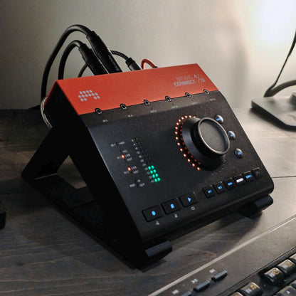 3D printed Bitwig Connect Audio Interface 30 degree stand by Cold Earth Industries, shown in black on a desk in a music studio, holding a Bitwig Connect