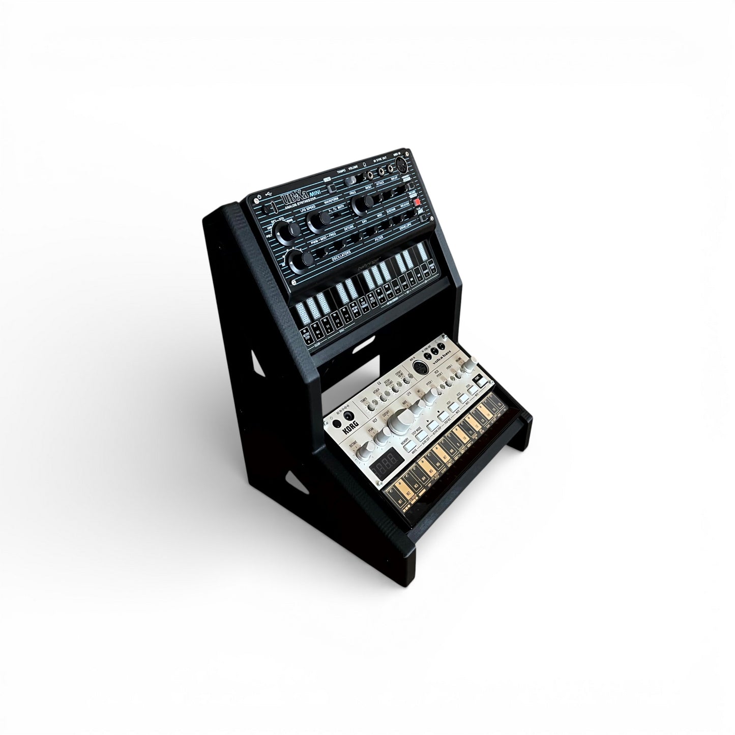 3D printed 2-Tier Korg Volca Roland Aira Behringer Mini | 30 / 60 Degrees | 195mm Width stand by Cold Earth Industries, shown holding Behringer Mini and Korg Volca, in black on a white background – custom desktop stands.