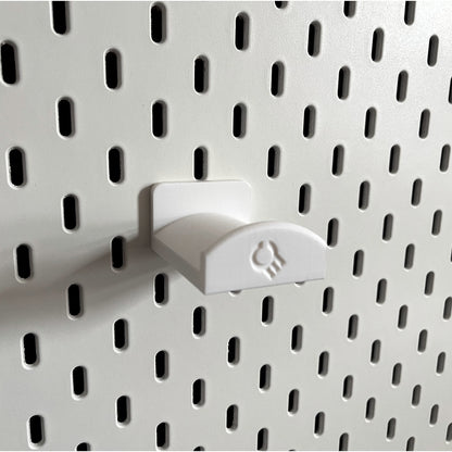3D printed  Headphone Holder for IKEA SKADIS UPPSPEL Headphones by Cold Earth Industries, shown in White, on a white Ikea Skadis Pegboard– custom studio and live performance gear.