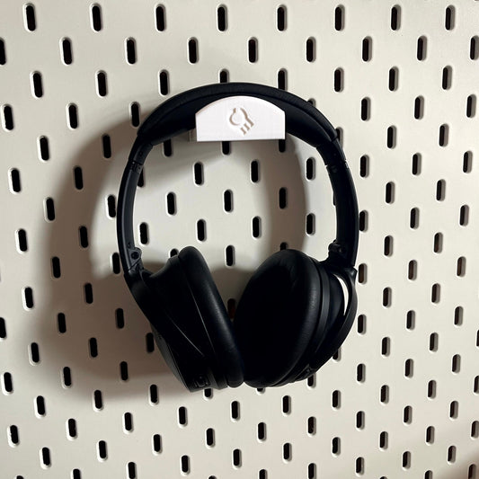 3D printed  Headphone Holder for IKEA SKADIS UPPSPEL Headphones by Cold Earth Industries, shown in White, holding black headphones, on a white Ikea Skadis Pegboard– custom studio and live performance gear.