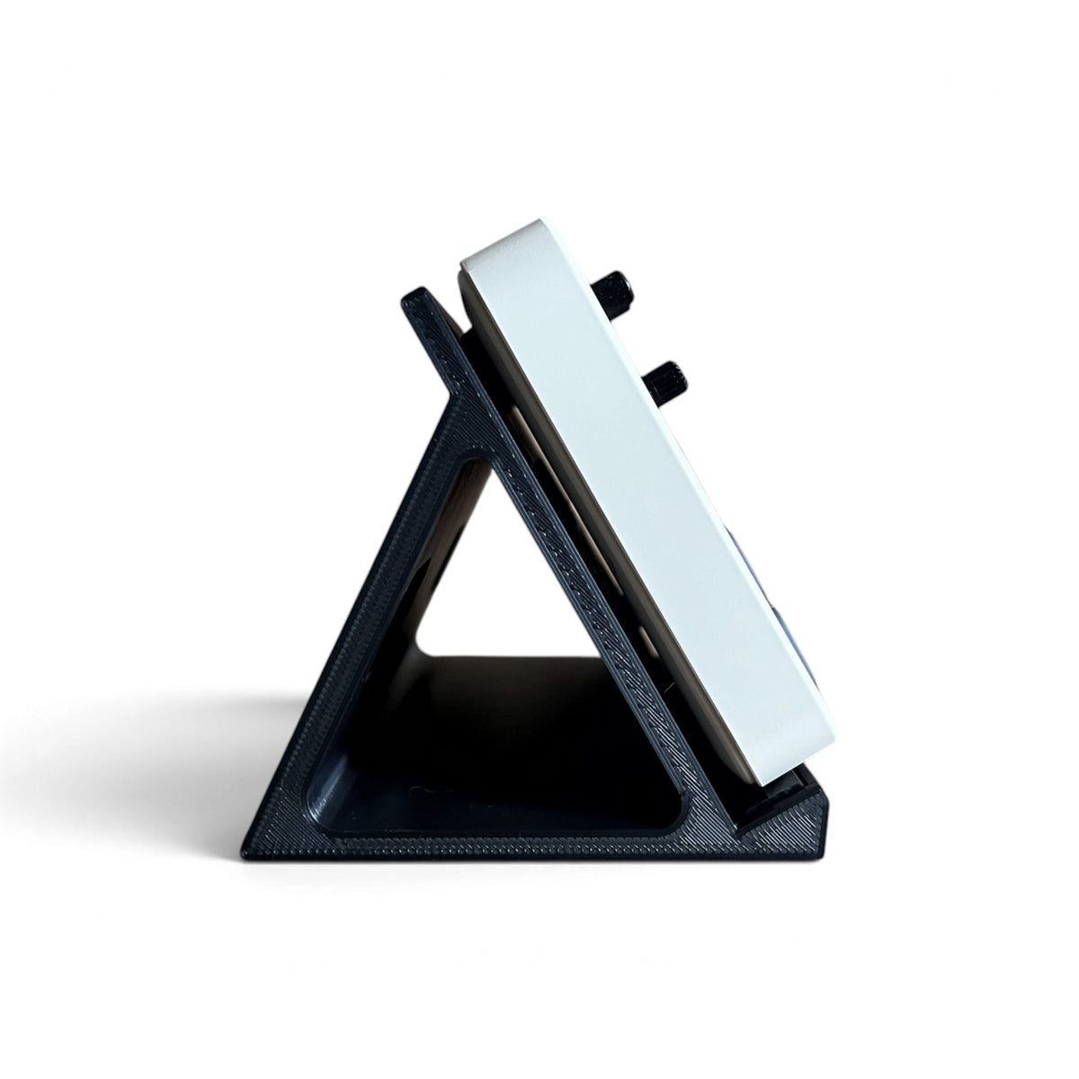 3D printed M-Vave FM-1 Synth 60 degree stand by Cold Earth Industries, shown side view, in black, on a white background holding an FM-1.
