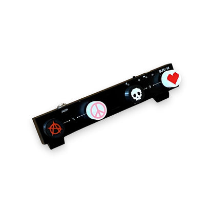 3D printed guitar pedal footswitch toppers with various designs including a heart, skull, anarchy symbol, and peace symbol, printed in black with colorful icons on a guitar pedal.